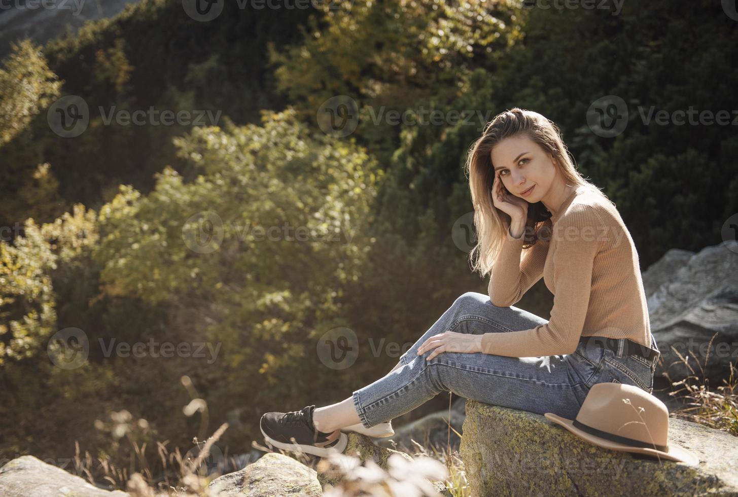 ung kvinna på en vandringsresa sitter på en sten foto