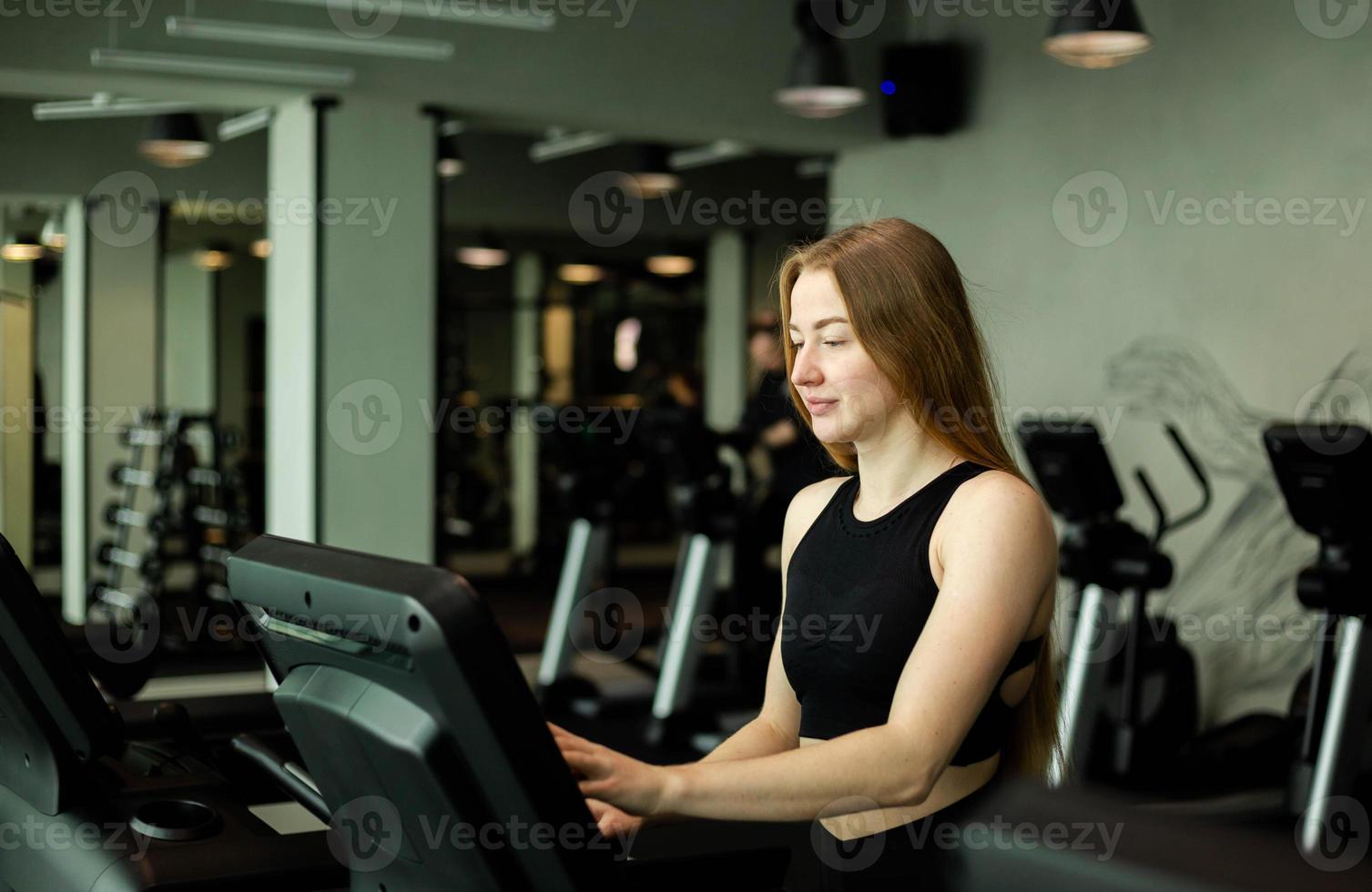 glad atletisk kvinna joggar på löpband i ett gym. foto