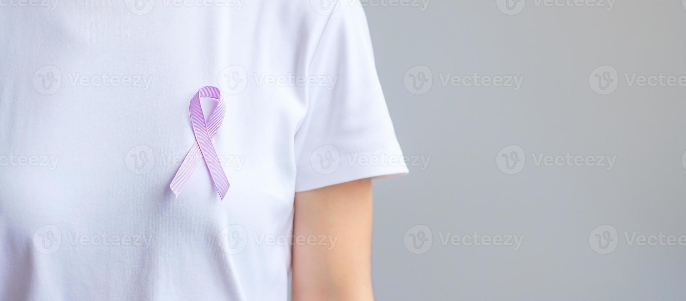 världscancerdagen. kvinna hand som håller lavendel lila band för att stödja människor som lever och sjukdom. hälsovård och medicinsk koncept foto