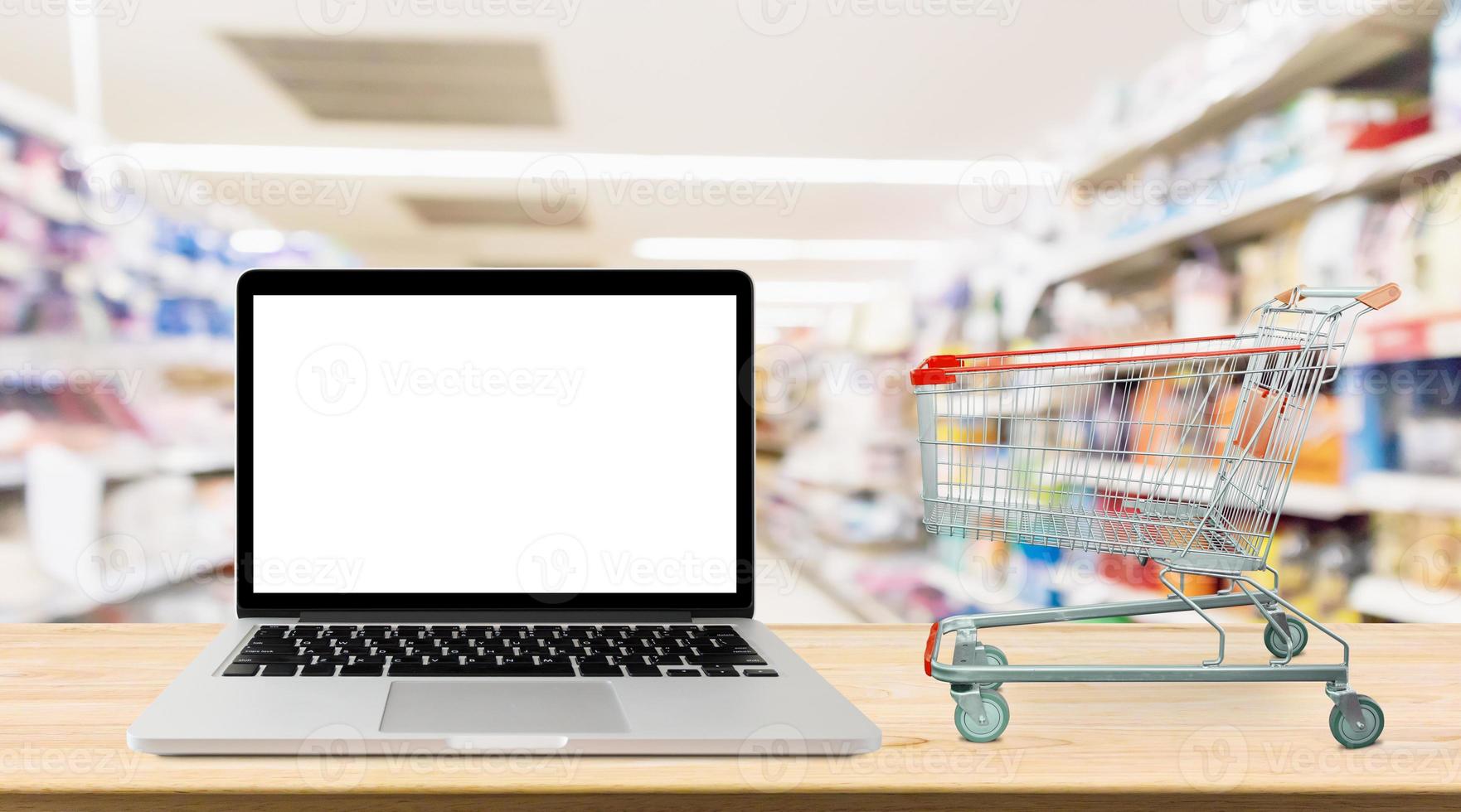 bärbar dator på träbord med supermarket gång suddig bakgrund online shopping koncept foto