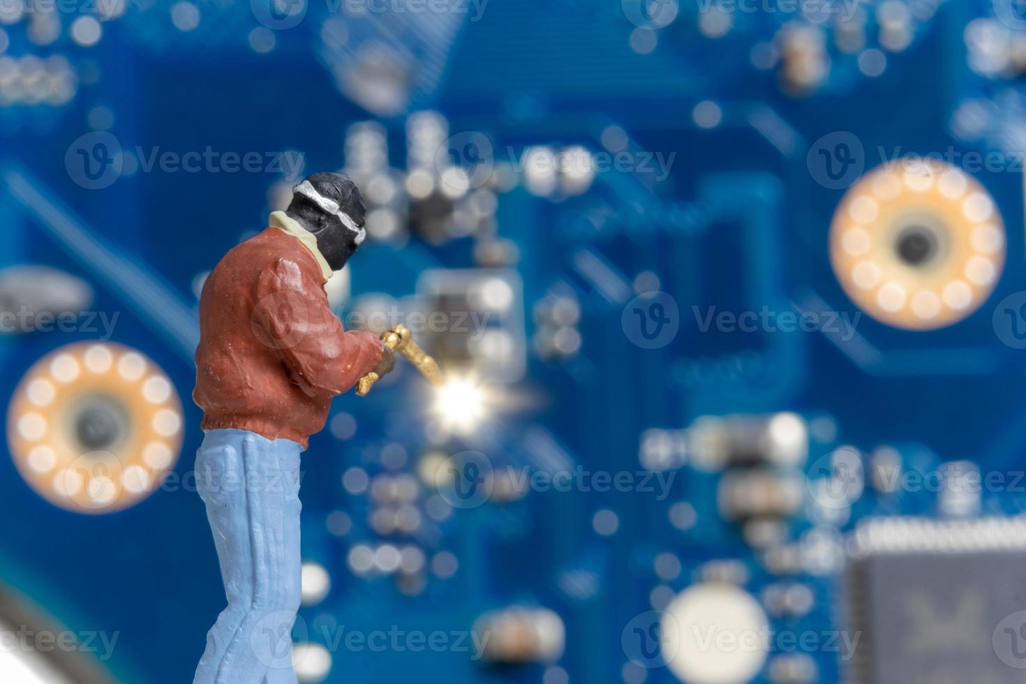 miniatyr människor datorreparationstekniker reparerar en elektronisk styrelse med gas foto