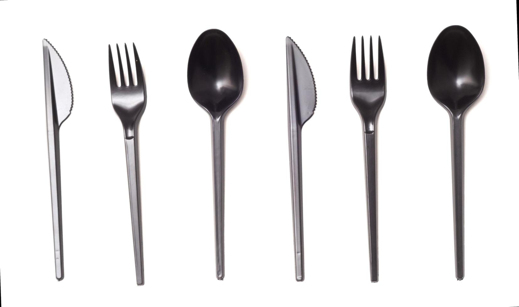 upprepande svart plast engångskniv, sked och gaffel isolerad på vitt, ovanifrån. foto