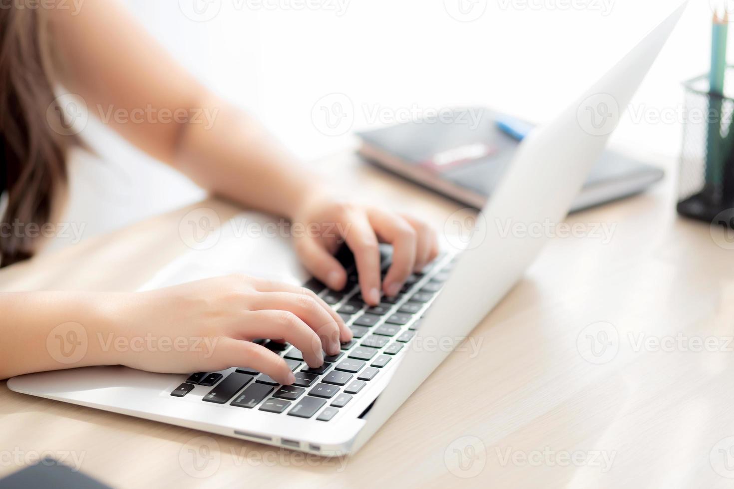 närbild frilansande asiatisk kvinna som arbetar och skriver på bärbar dator vid skrivbordskontoret med professionell, tjej som använder anteckningsboken kontrollerar e-post eller socialt nätverk, affärs- och livsstilskoncept. foto