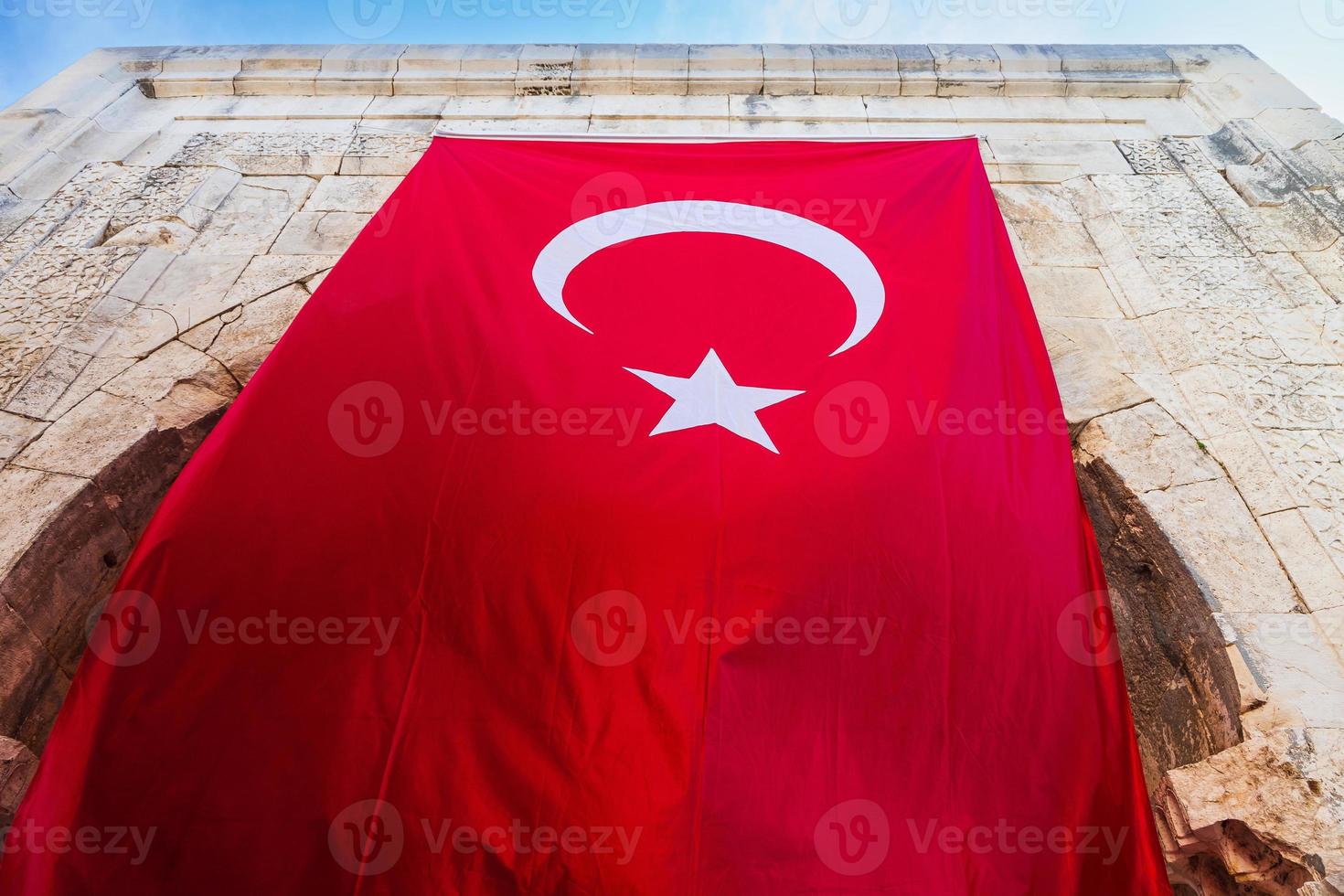 närbild av den turkiska nationalflaggan hängande på en gammal stenbyggnad foto