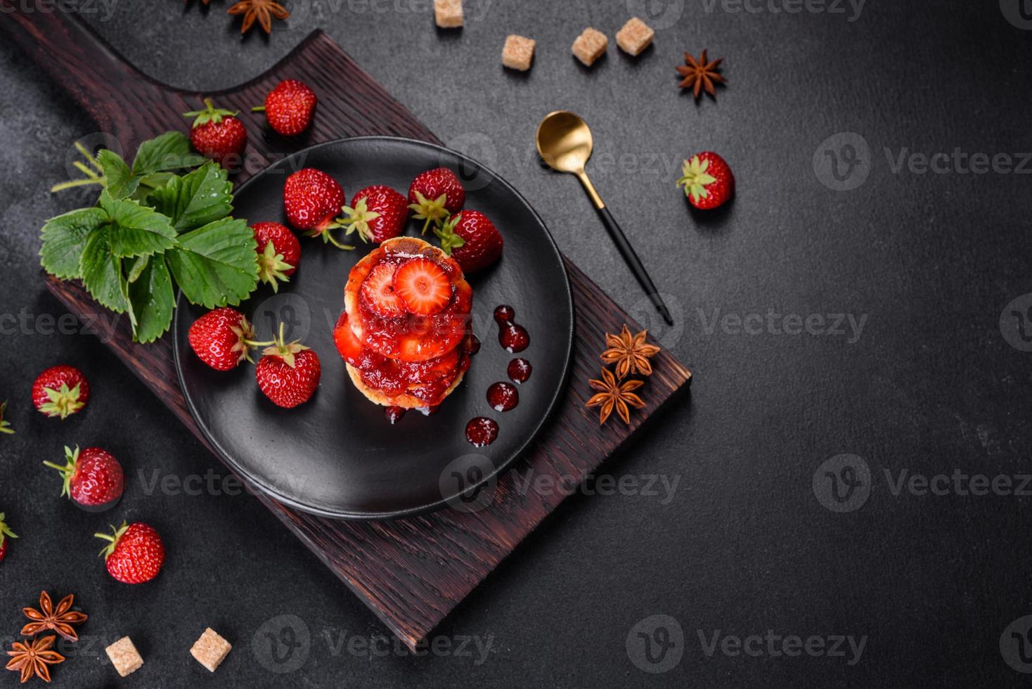 kesopannkakor med skivade jordgubbar och jordgubbssylt på en tallrik på en betongbakgrund foto