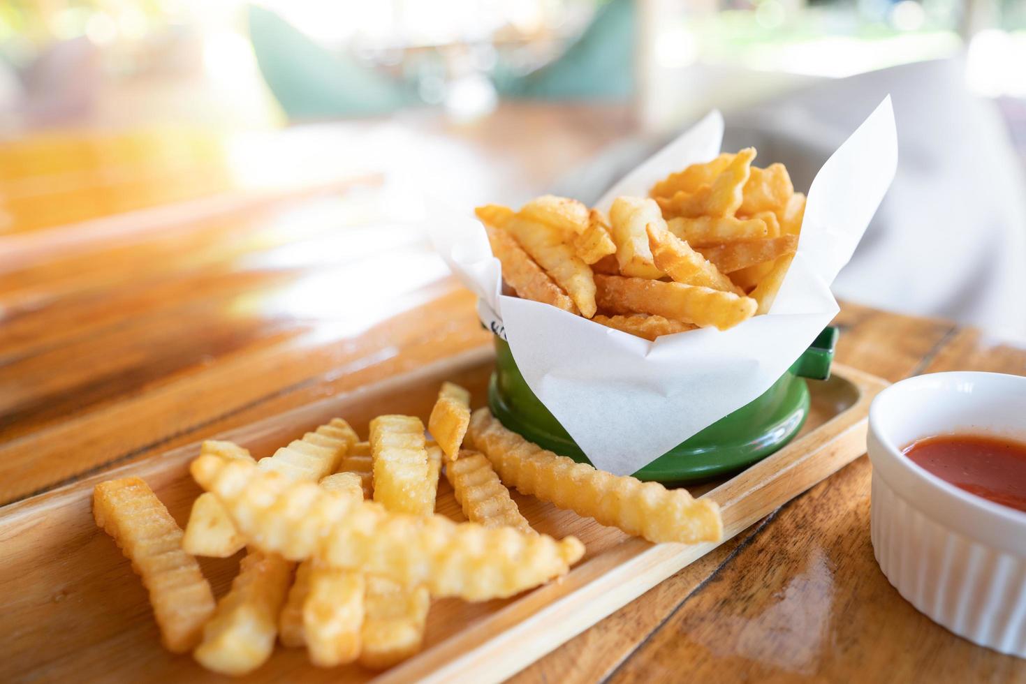 pommes frites i en grön emaljbehållare, på ett thailändskt träbord foto