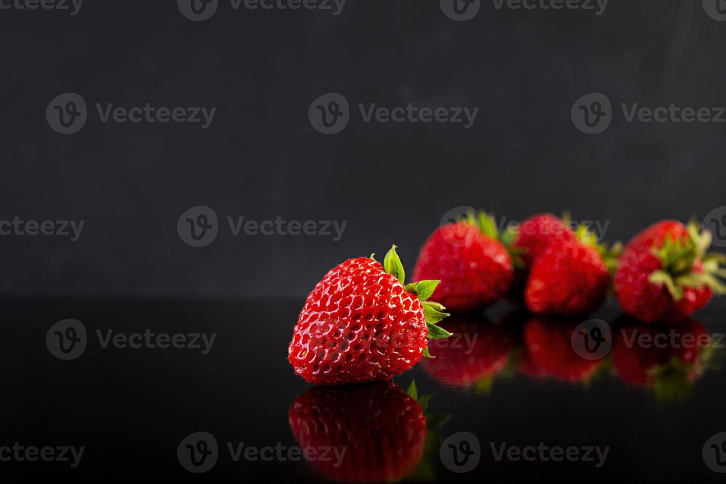 söt färsk mogen jordgubbe isolerad på mörk bakgrund. foto