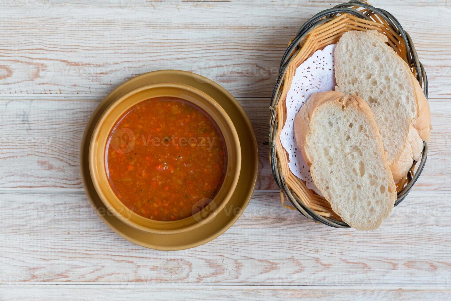skål med minestronsoppa med bröd på träbord foto