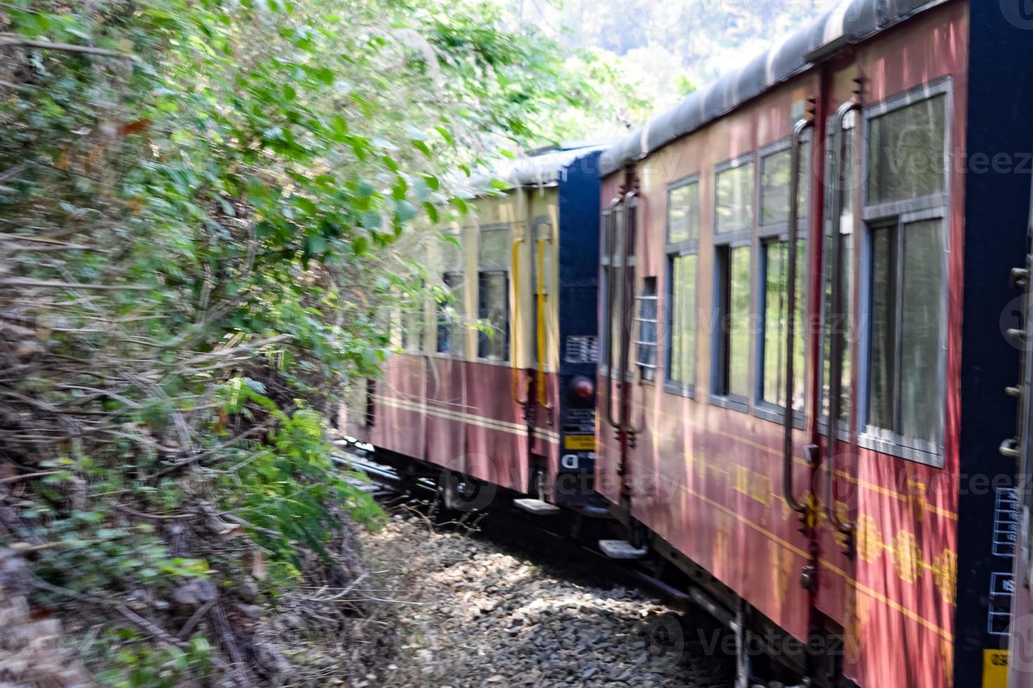 leksakståg rör sig på bergssluttningar, vacker utsikt, ena sidan berg, ena sidan dalen rör sig på järnväg till kullen, bland grön naturskog. leksakståg från kalka till shimla i Indien foto