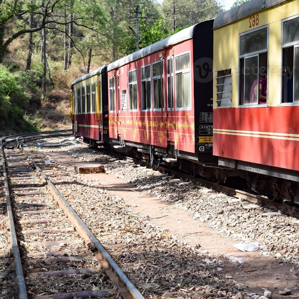 leksakståg rör sig på bergssluttningar, vacker utsikt, ena sidan berg, ena sidan dalen rör sig på järnväg till kullen, bland grön naturskog. leksakståg från kalka till shimla i Indien foto