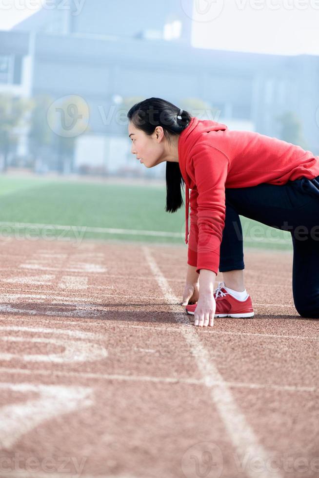 atletisk kinesisk kvinna i startposition på banan foto
