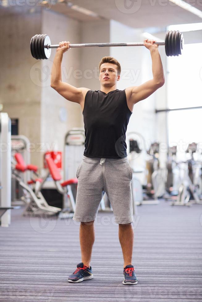 ung man böja muskler med skivstång i gymmet foto