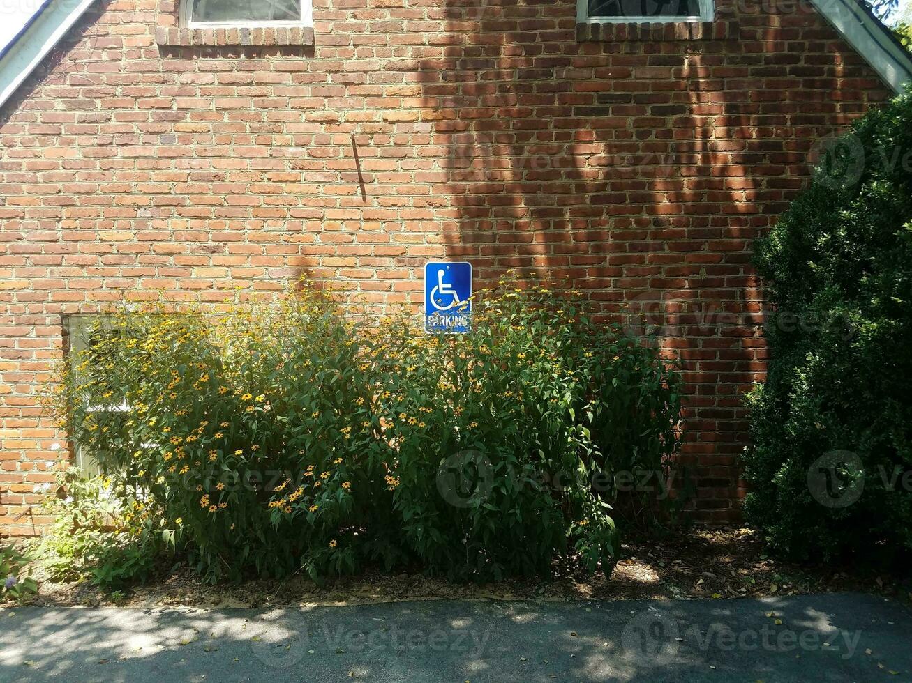 röd tegelvägg med blå handikappparkeringsskylt foto