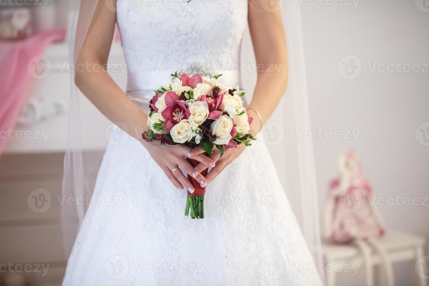 vita rosor i händerna på bruden foto