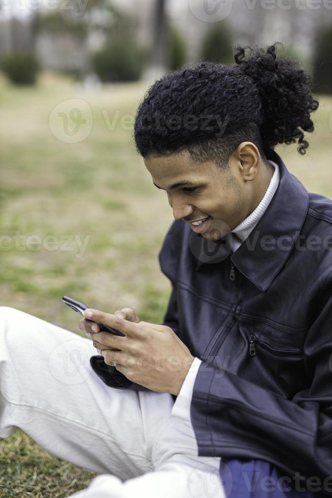 ung afroamerikansk man med en mobiltelefon foto