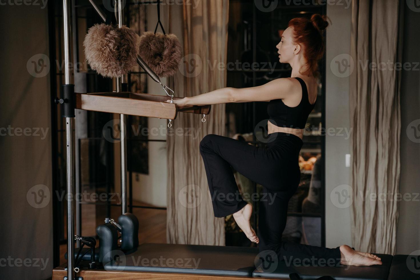 ung pilatesinstruktör med atletisk kropp som tränar på cadilac reformer foto