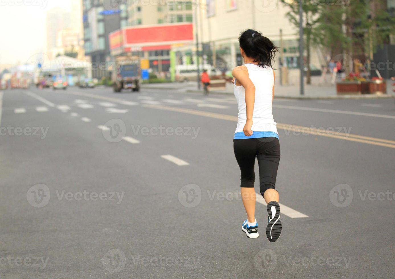 hälsosam livsstil fitness sport kvinna kör på stadsvägen foto