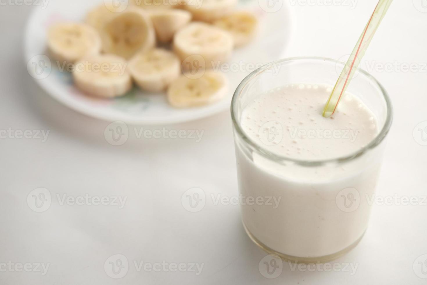 närbild av skiva banan glas mjölk på bordet foto