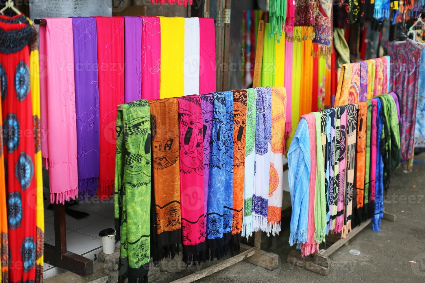 rader med färgglada silkesjalar som hänger på en marknad foto
