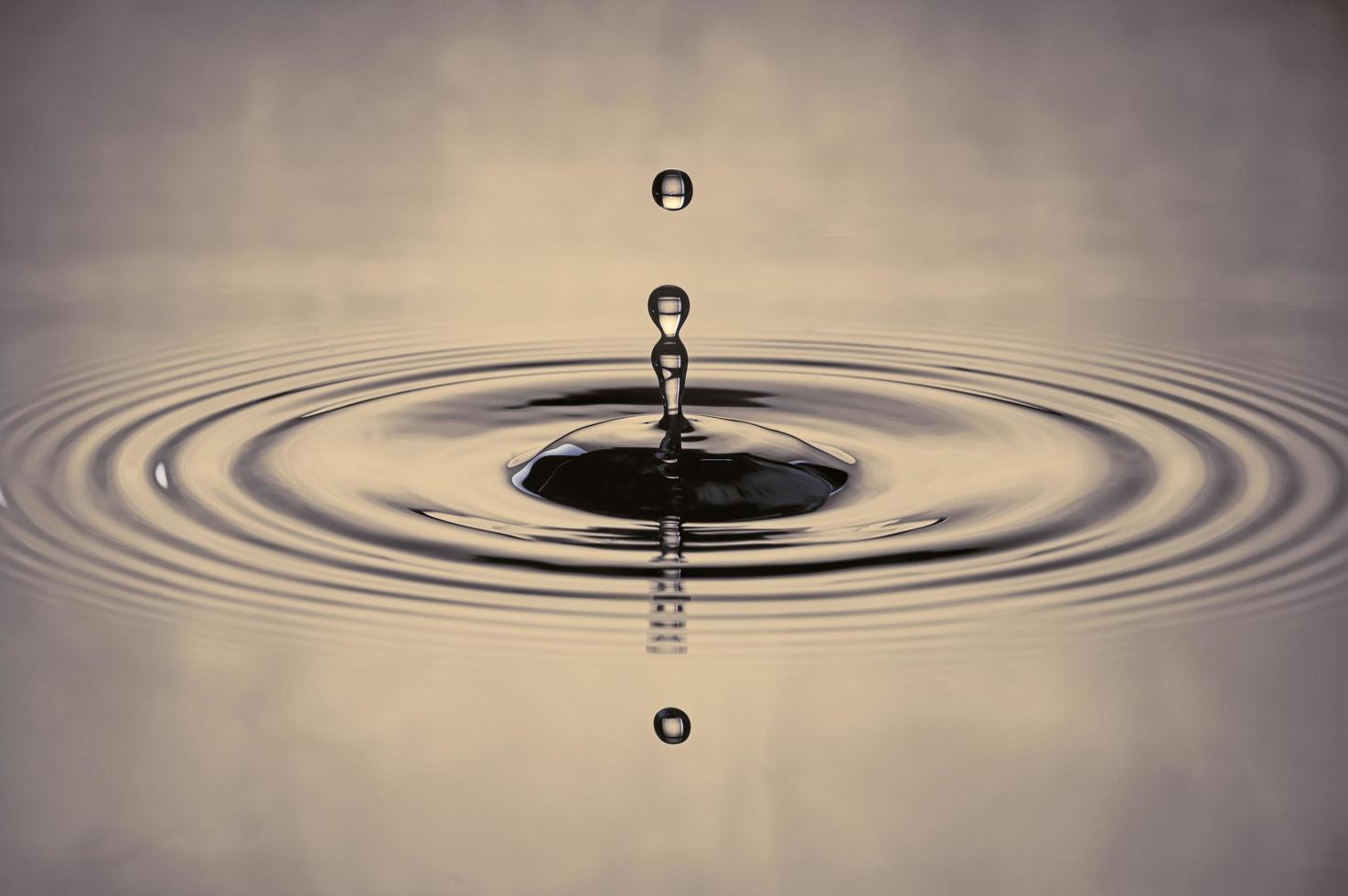 vattendroppar stänker i en gråfärgad spruta av vatten som droppar och reflekterar vatten.i dammen dimman. foto