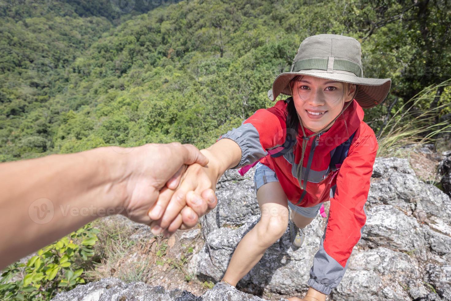 hjälpande hand. hiker kvinna få hjälp på vandring leende glad övervinna hinder. turist backpackers gå på berget, ungt par reser. foto