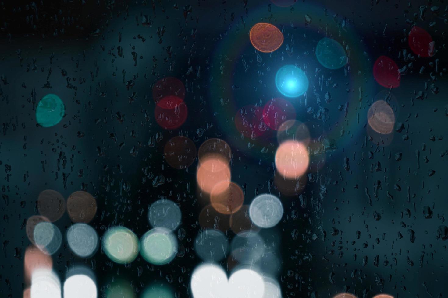 droppar på fönstret med gatubelysningsbakgrund på natten foto