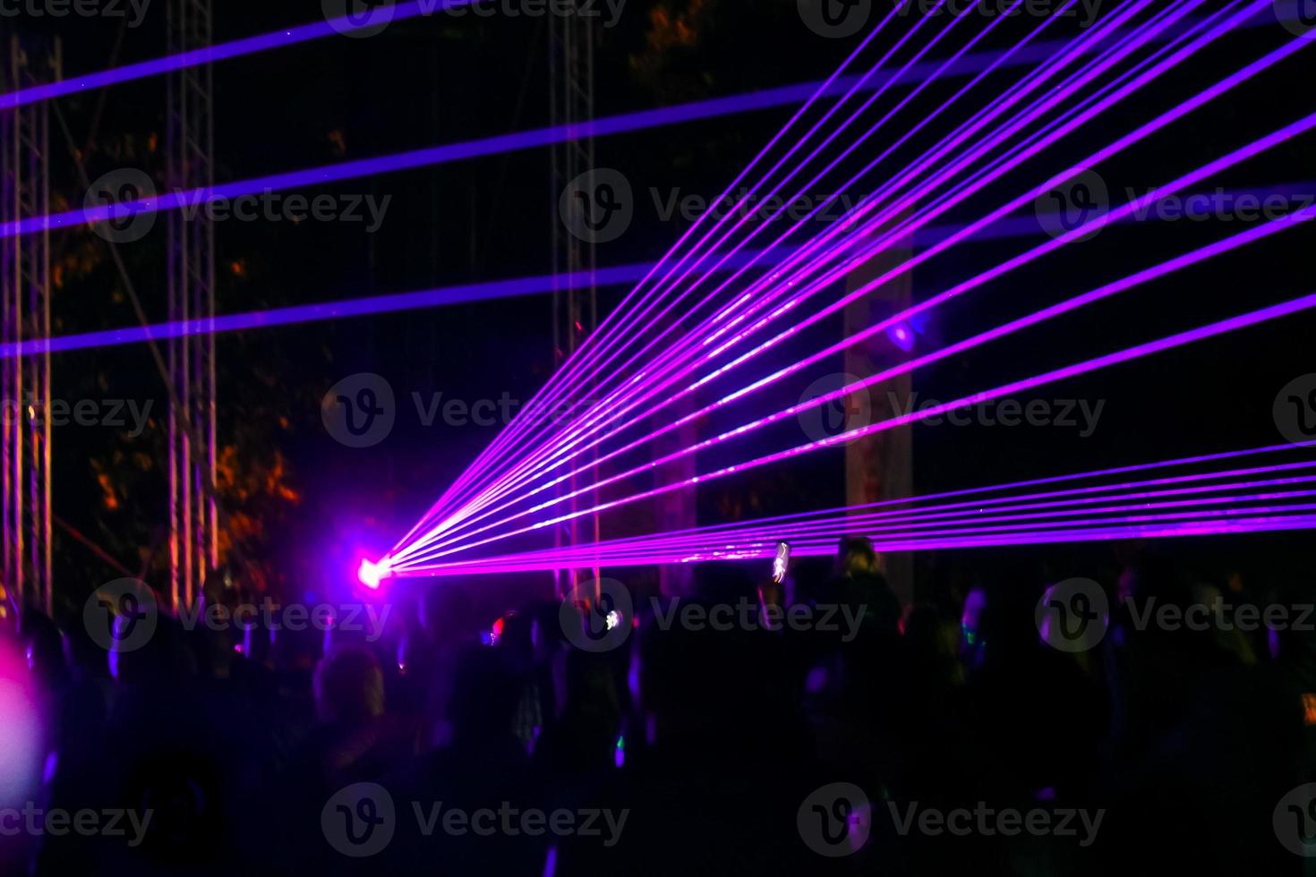 lila laser neonstrålar. folkmassa som tittar på lasershow på gatufestival. foto