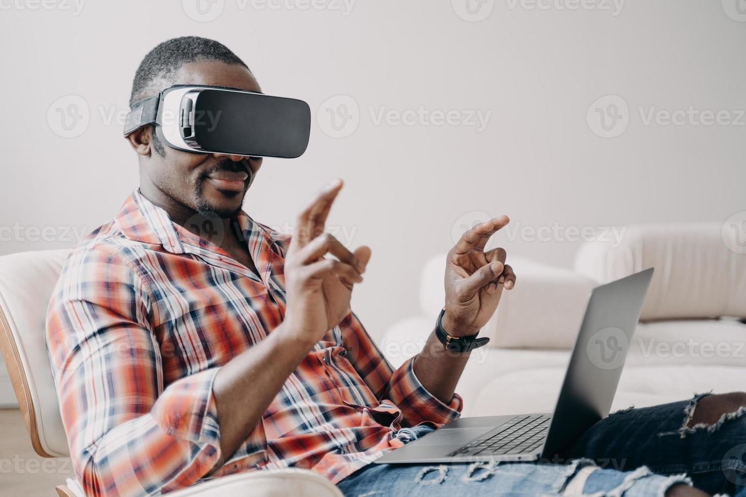 afrikansk amerikansk kille mjukvaruutvecklare i virtuell verklighetsglasögon som arbetar i cyberrymden på bärbar dator foto