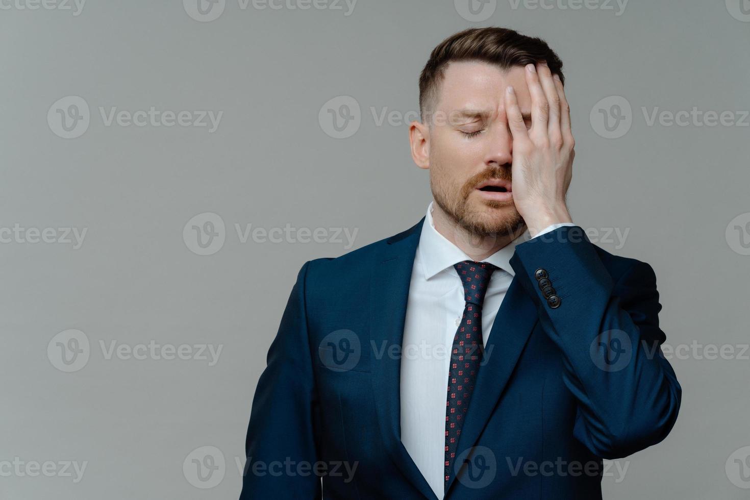 horisontell bild av missnöjd skäggig man chef gör ansikte handflatan känns väldigt trött klädd i formell outfit är deprimerad isolerad över grå bakgrund med kopia utrymme för din annons foto