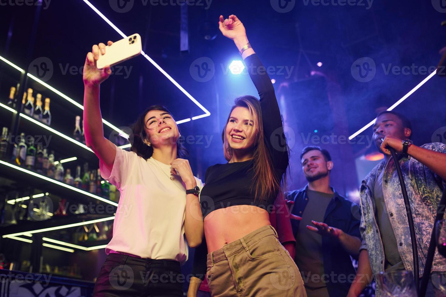 två kvinnor som gör selfie. grupp vänner som har roligt på nattklubben tillsammans foto