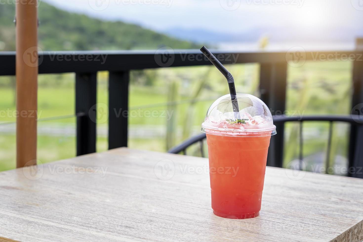 uppfriskande drink för sommaren, isbärsjuice i en plastbägare med suddig grön bakgrund. ekologisk för hälsosam, perfekt drink för sommaren och kopiera utrymme för text. semester och hälsosam dryck foto