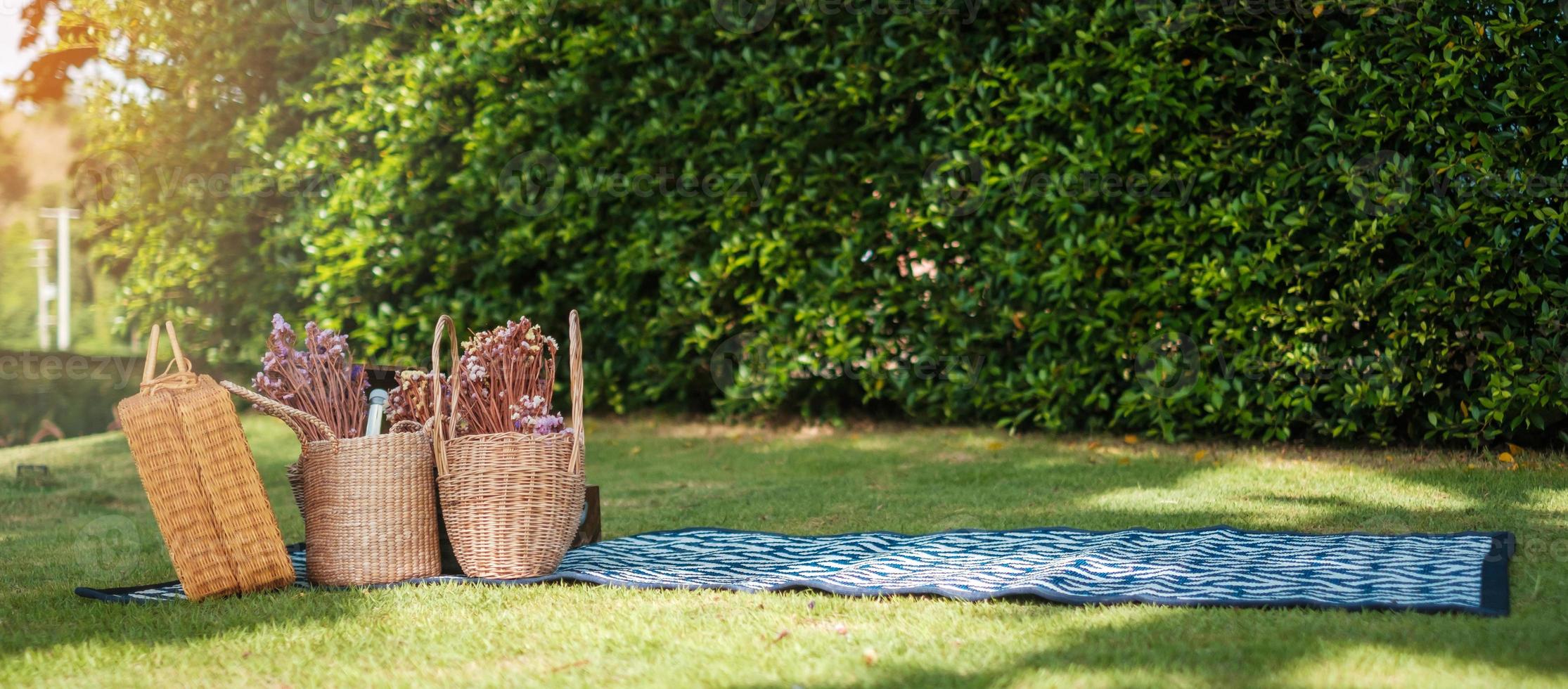 picknick i parken nära floden, torkade blommor, korgar vinflaska, bok och retro grammofon vinylskiva. sommar, vår och semester koncept foto