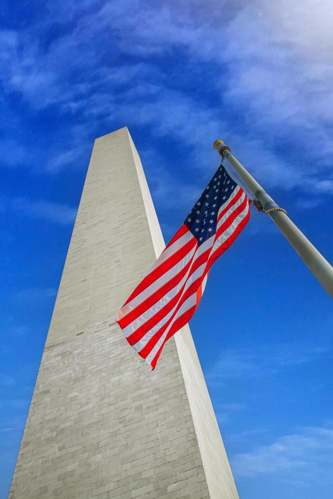 Washington monument med USAs flagga på en solig dag. foto