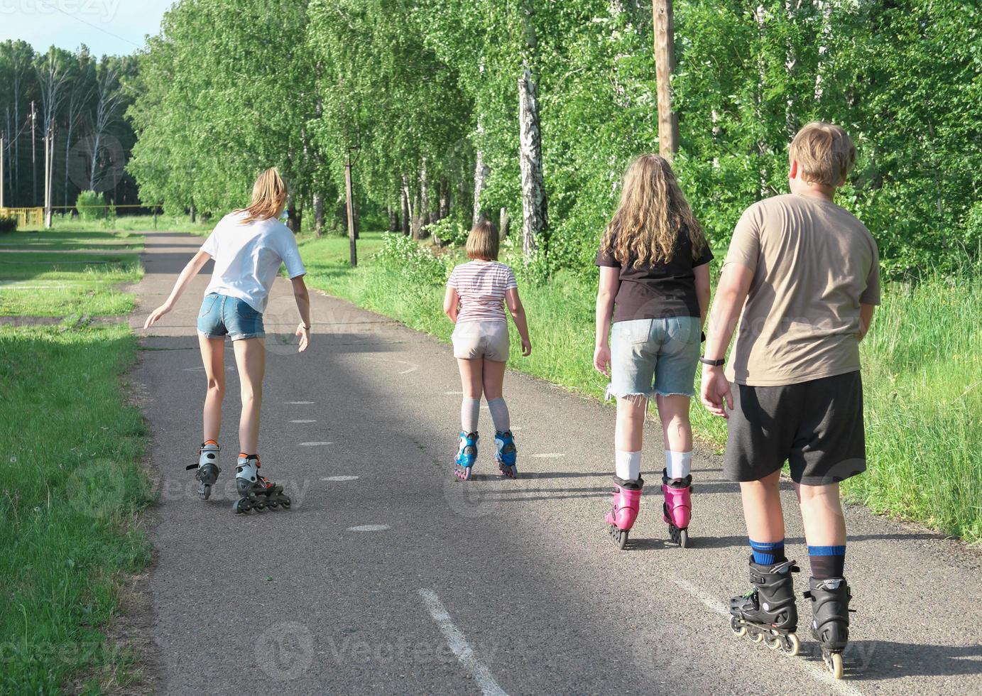 tonåringar rullskridskor på gatan. vänner tillsammans på landsbygden. bakifrån av barn. fritid och sport på sommaren. foto