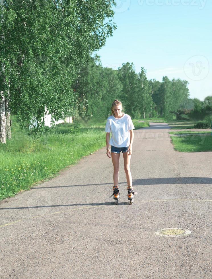 tonåring flicka rullskridskor i sommar park. smal sportig tjej som bär vardagskläder. aktiv fritid för tiotals foto