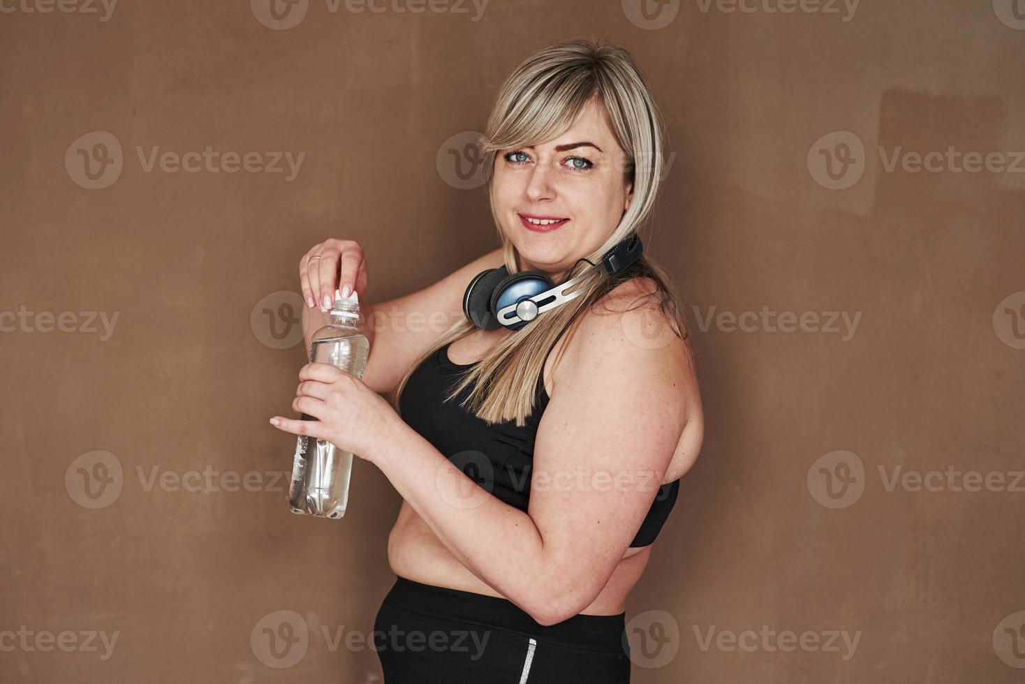 blond kvinna i studion står mot brun bakgrund foto