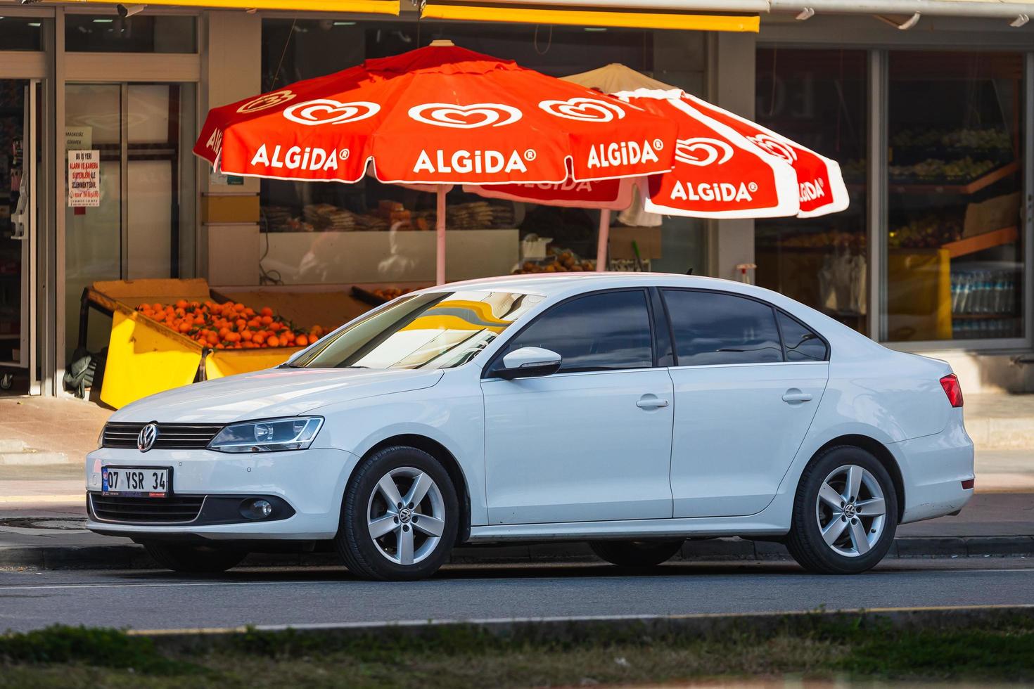 antalya turkiet mars 04 2022 vit volkswagen jetta är parkerad på gatan en varm sommardag mot bakgrund av en byggnad, butiker foto