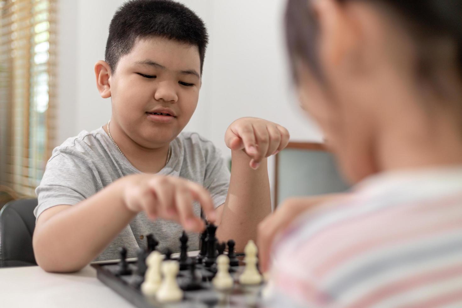 liten pojke och liten flicka spelar schack hemma. barn spelar schack foto