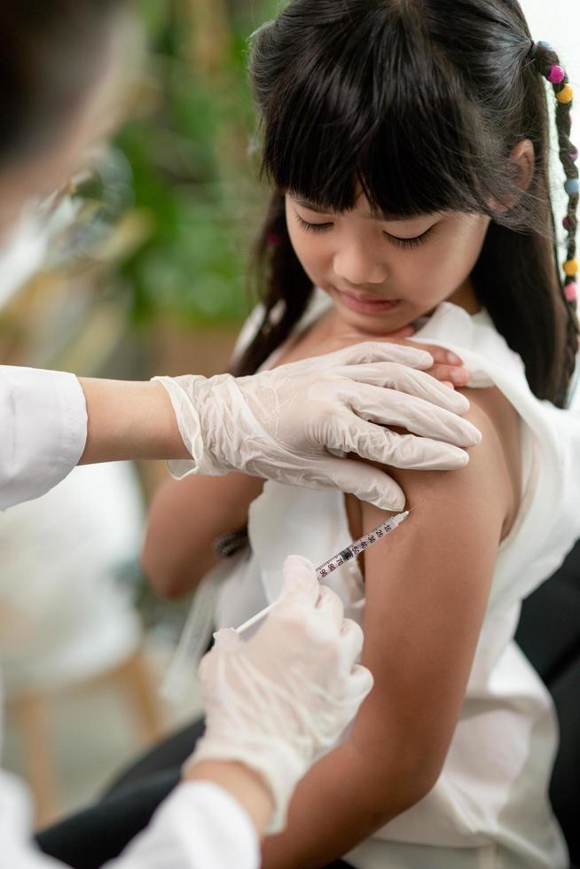 vaccination koncept. kvinnlig läkare vaccinerar söt liten flicka på kliniken foto