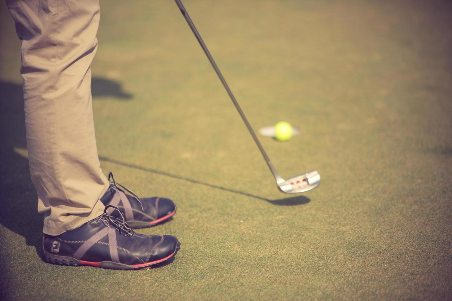golfspelare på puttinggreen slår bollen i en hole.vintage färg foto