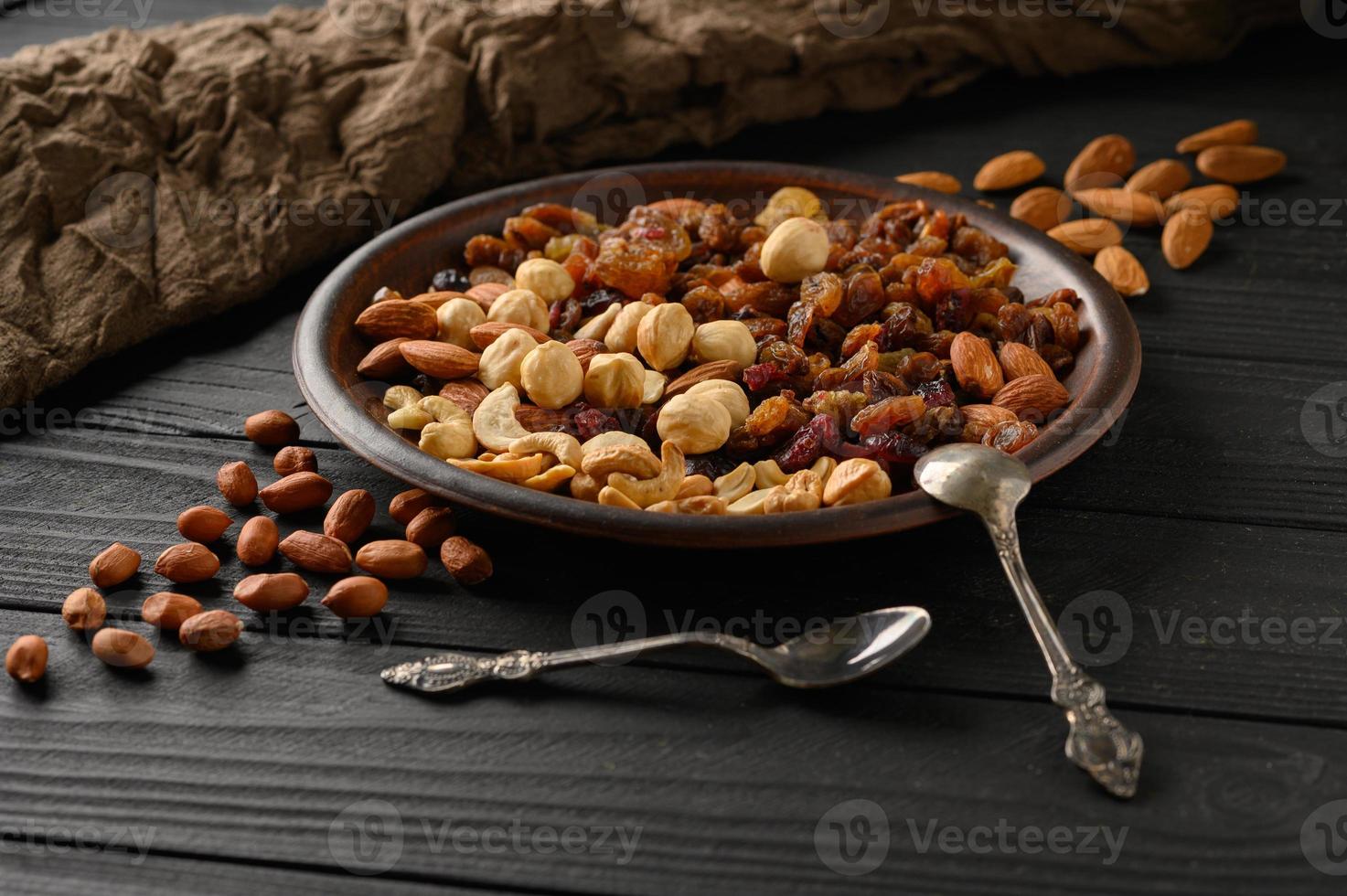hasselnötter, cashewnötter, russin, mandlar, jordnötter, valnötter på en svart träbakgrund foto