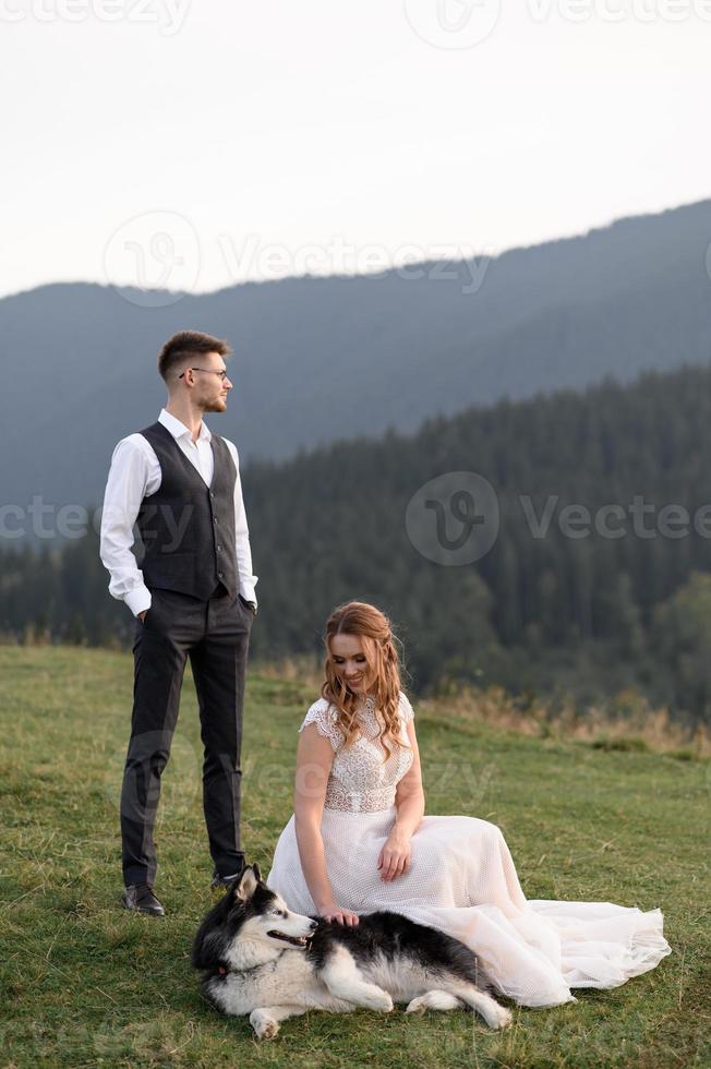 glada snygga brudparet springer och har kul i bergen en solig sommardag foto