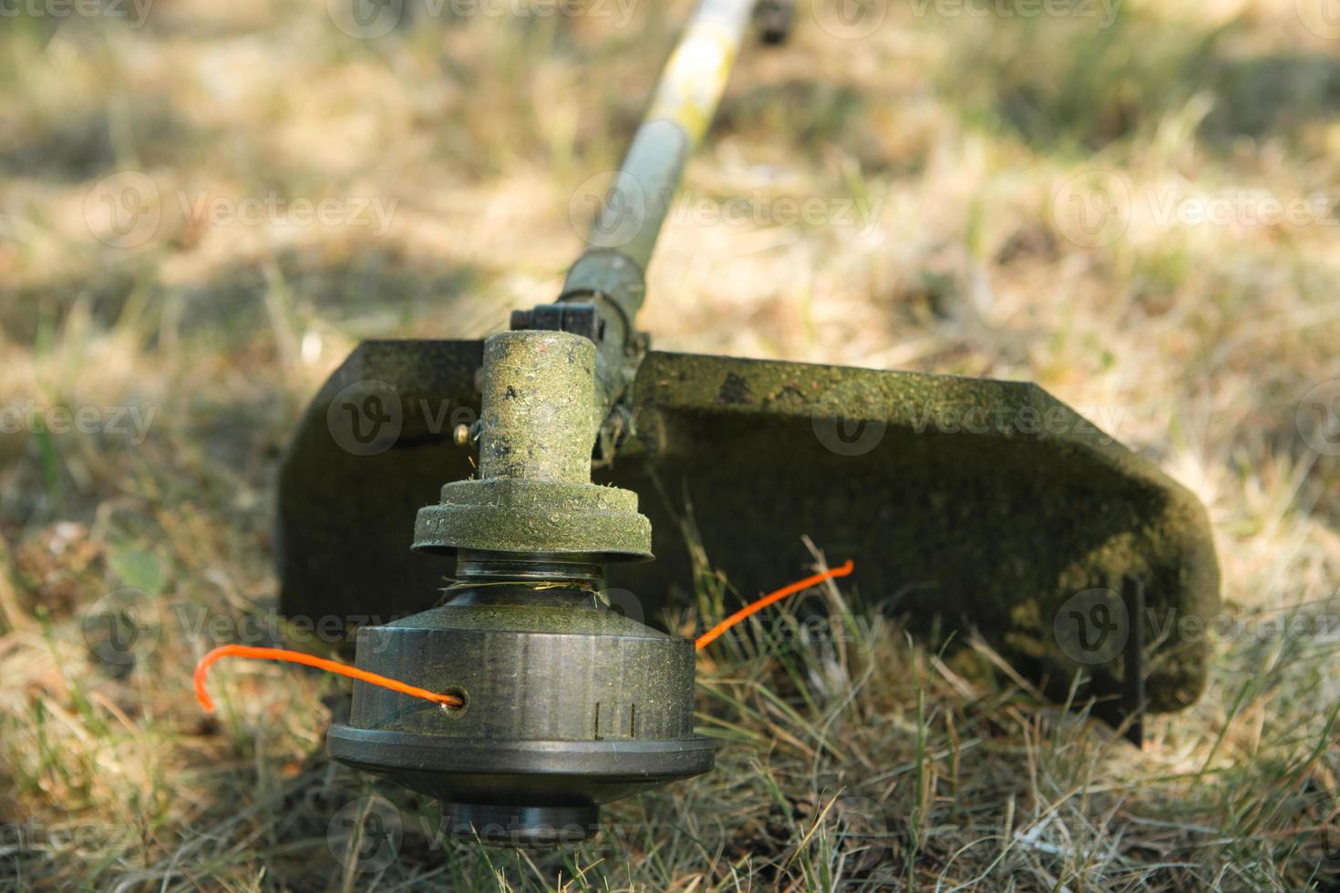 trimmer efter att ha klippt gräs närbild. bensinpump på gräset med skyddsglasögon. trädgårdsskötsel och trädgårdsskötsel av trädgårdstomten, gräsmatta skötsel. foto