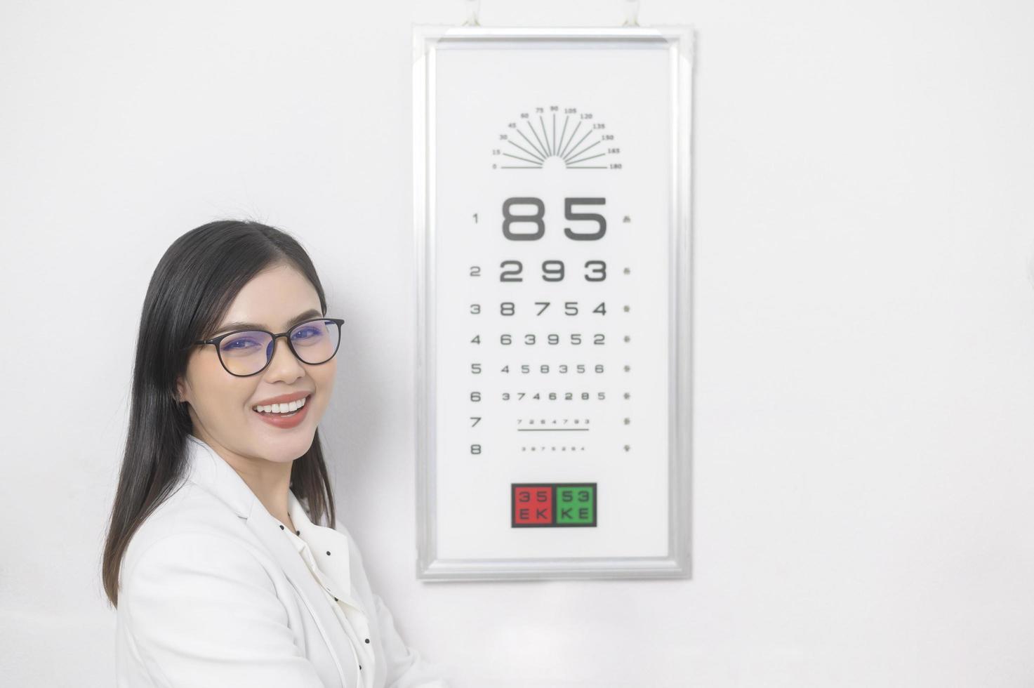 ung ögonläkare gör visuellt test för kund med ögondiagram i optiskt centrum, ögonvårdskoncept. foto