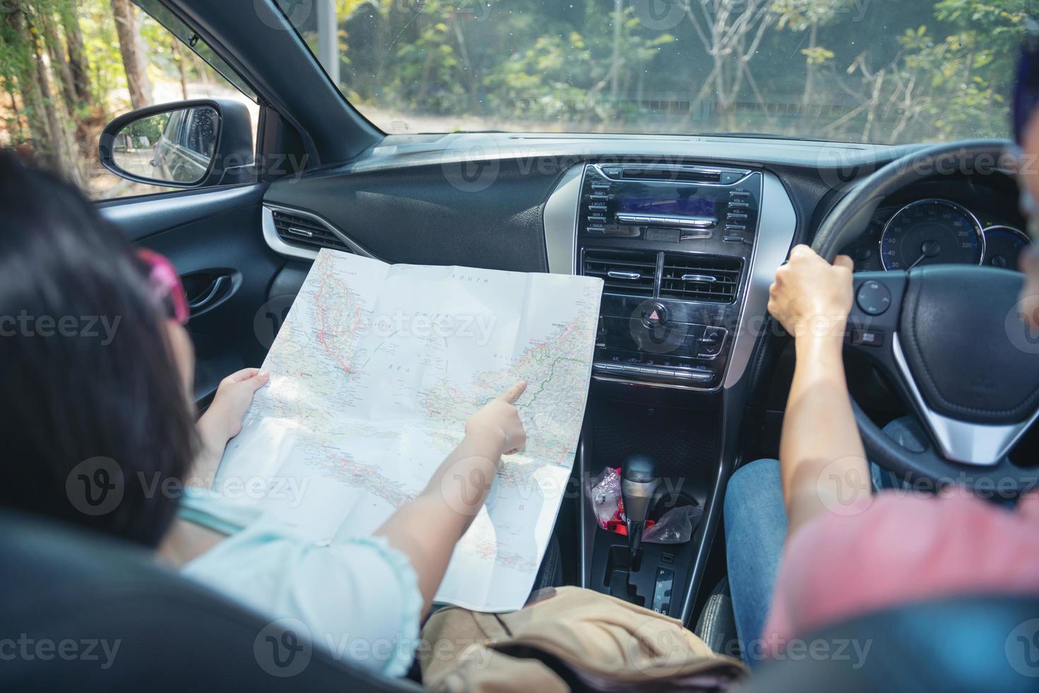 familjesemester tittar på kartan, lycklig familj på en bilresa i sin bil, mamma kör bil medan hennes dotter sitter bredvid, mamma och dotter reser. sommartur med bil. foto