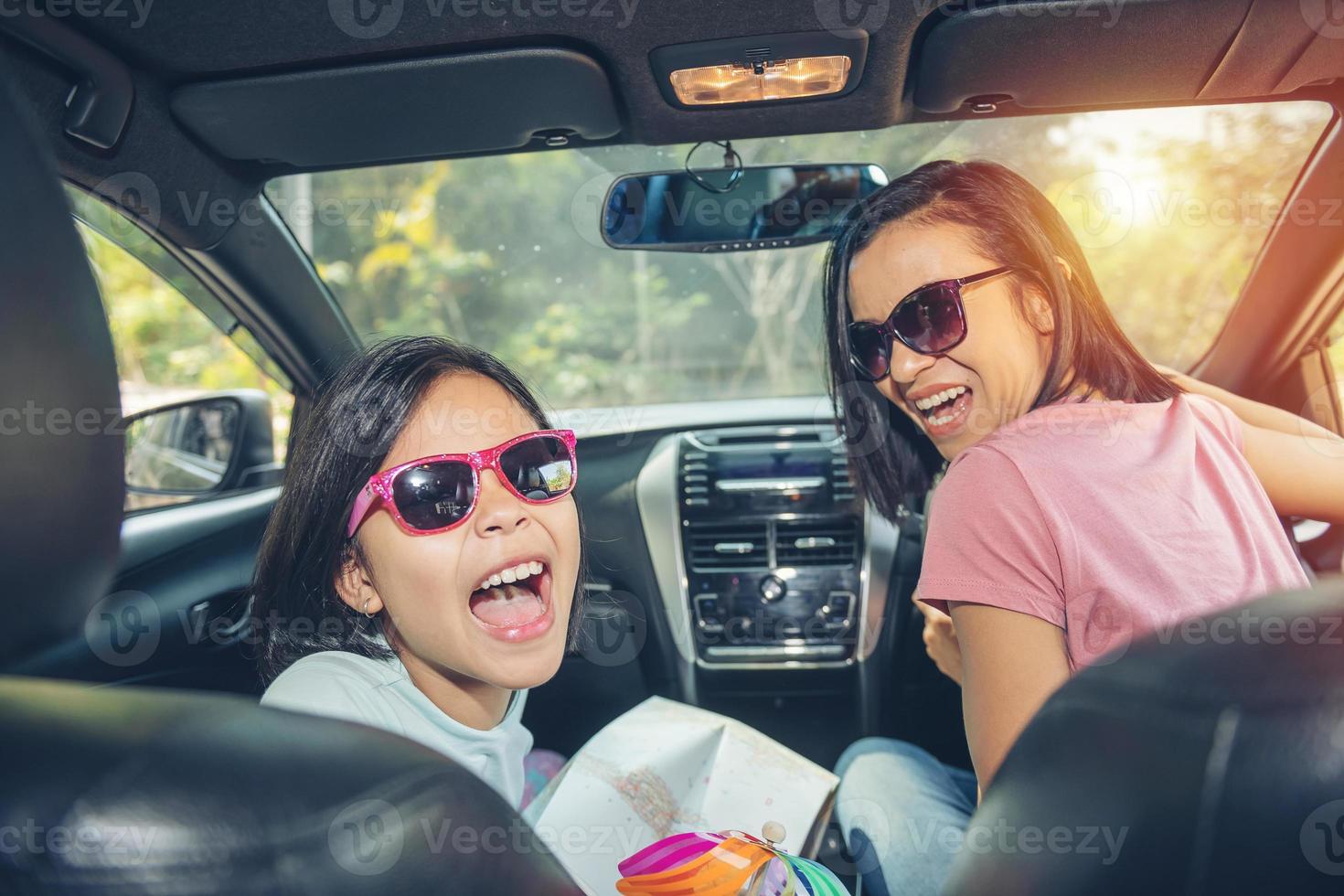 familjesemester, lycklig familj på roadtrip i sin bil, mamma kör bil medan hennes dotter sitter bredvid, mamma och dotter reser. sommartur med bil. foto