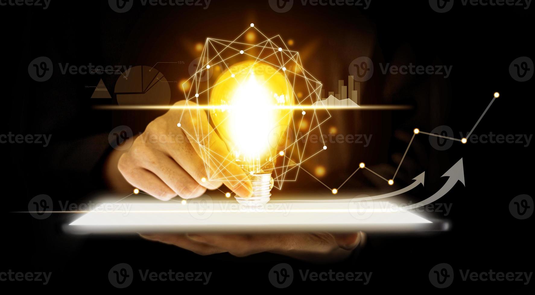 en person som håller en glödlampa placerad på en surfplatta, grafiska diagram och fluktuationer i finansiella data, som visar affärstillväxt. affärsstrategi. digital marknadsföring. digitalt affärshologram. foto
