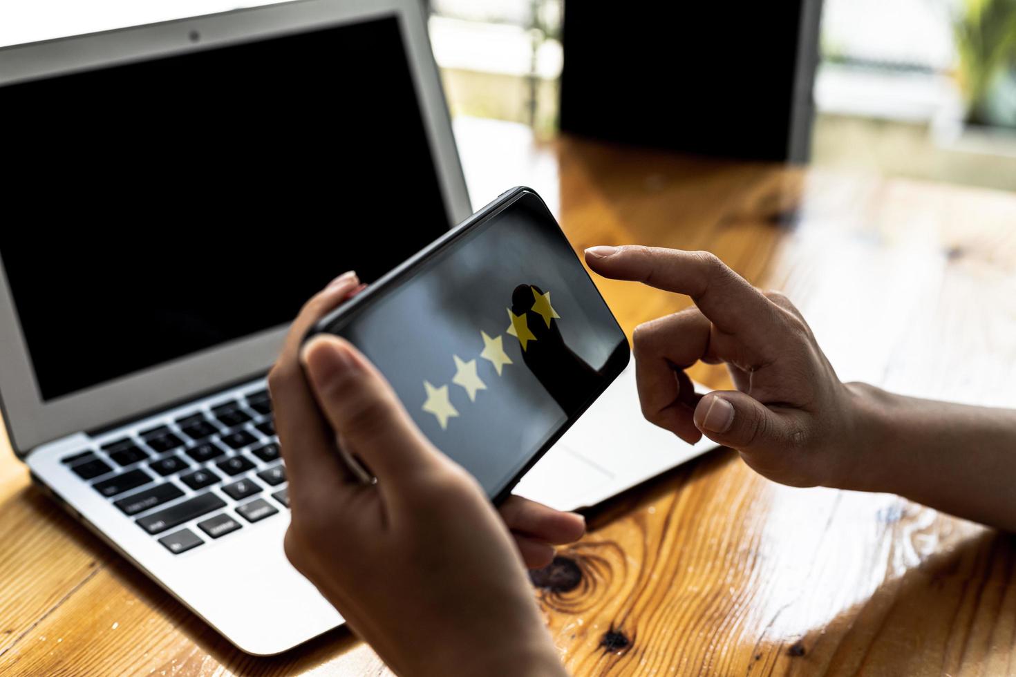 person som håller en smartphone med en skärm som visar 5 gula stjärnor, recenserar en produkt genom en online shoppingapplikation. konceptet att använda applikationer på smartphones via internetnätverket. foto