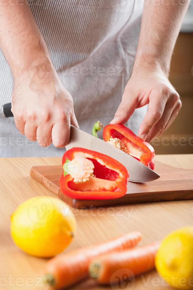 man skär paprika i köket foto