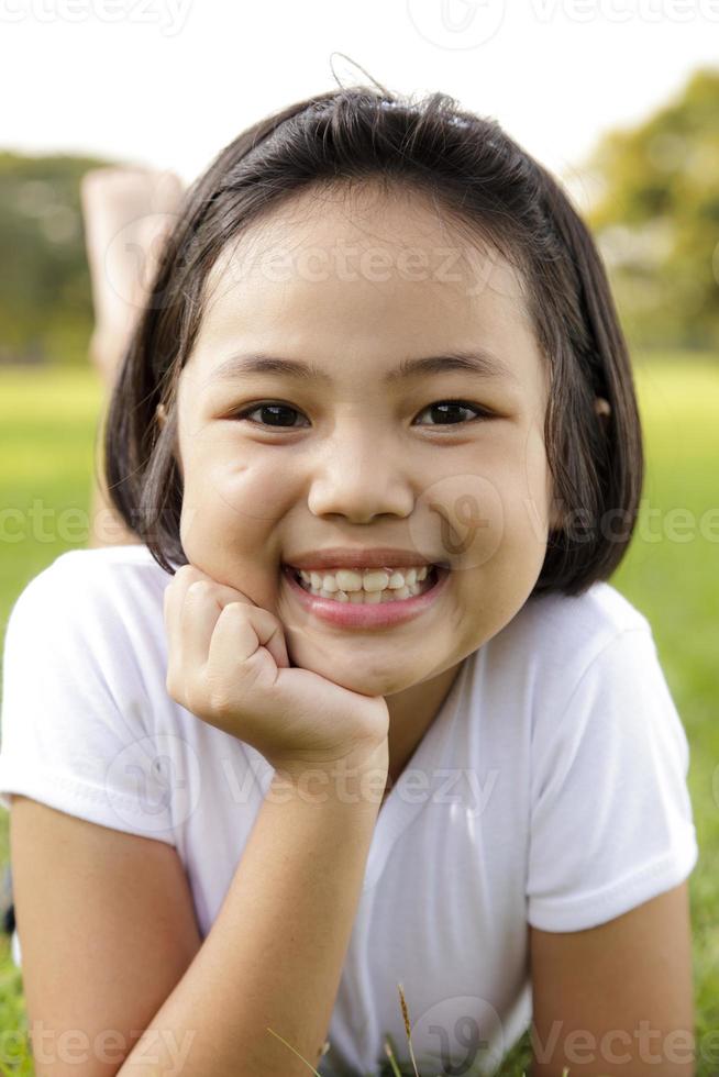 asiatisk liten flicka koppla av och ler glatt i parken foto